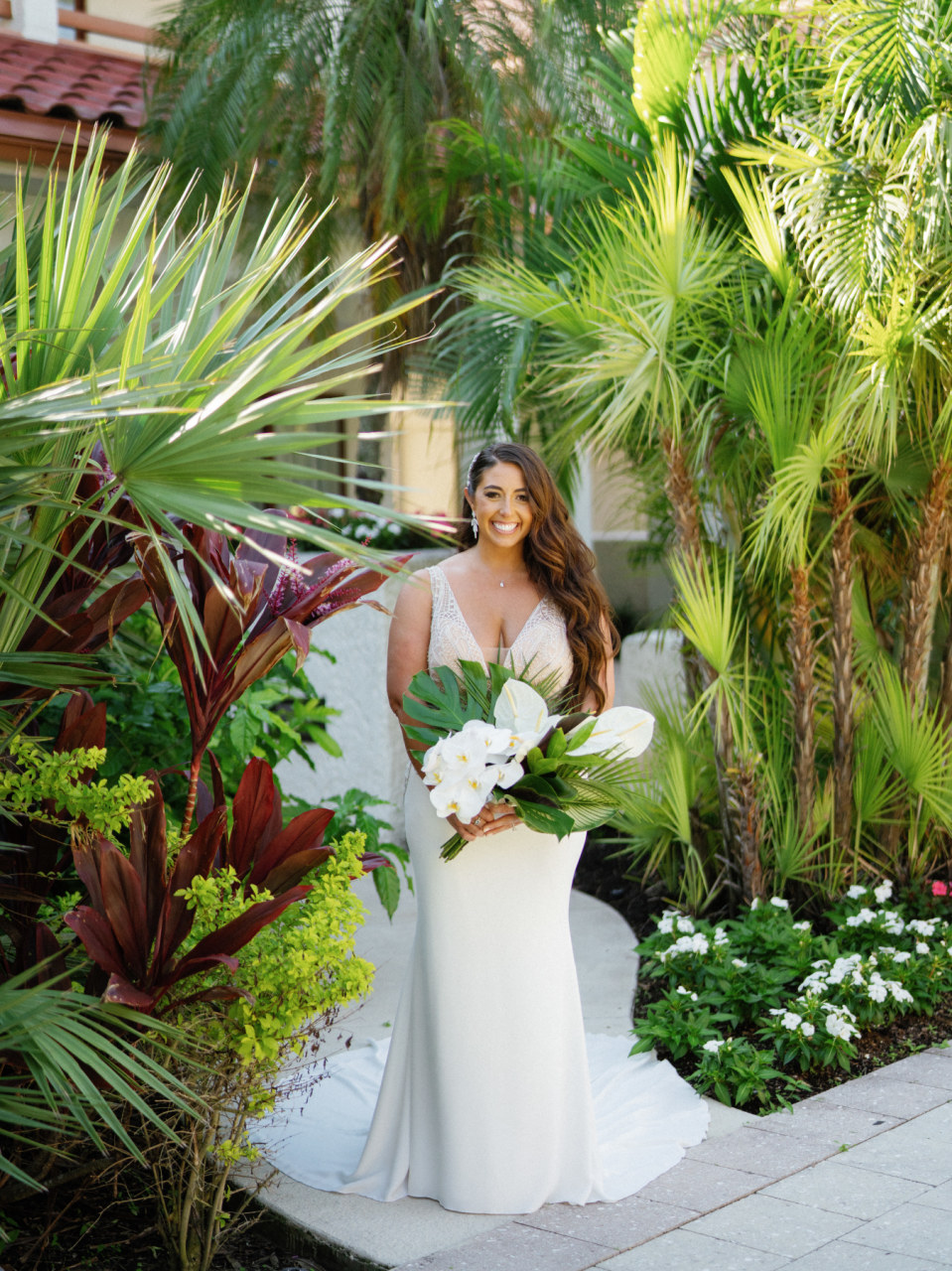 bride in satin wedding gown with white and palm leaves bouquet