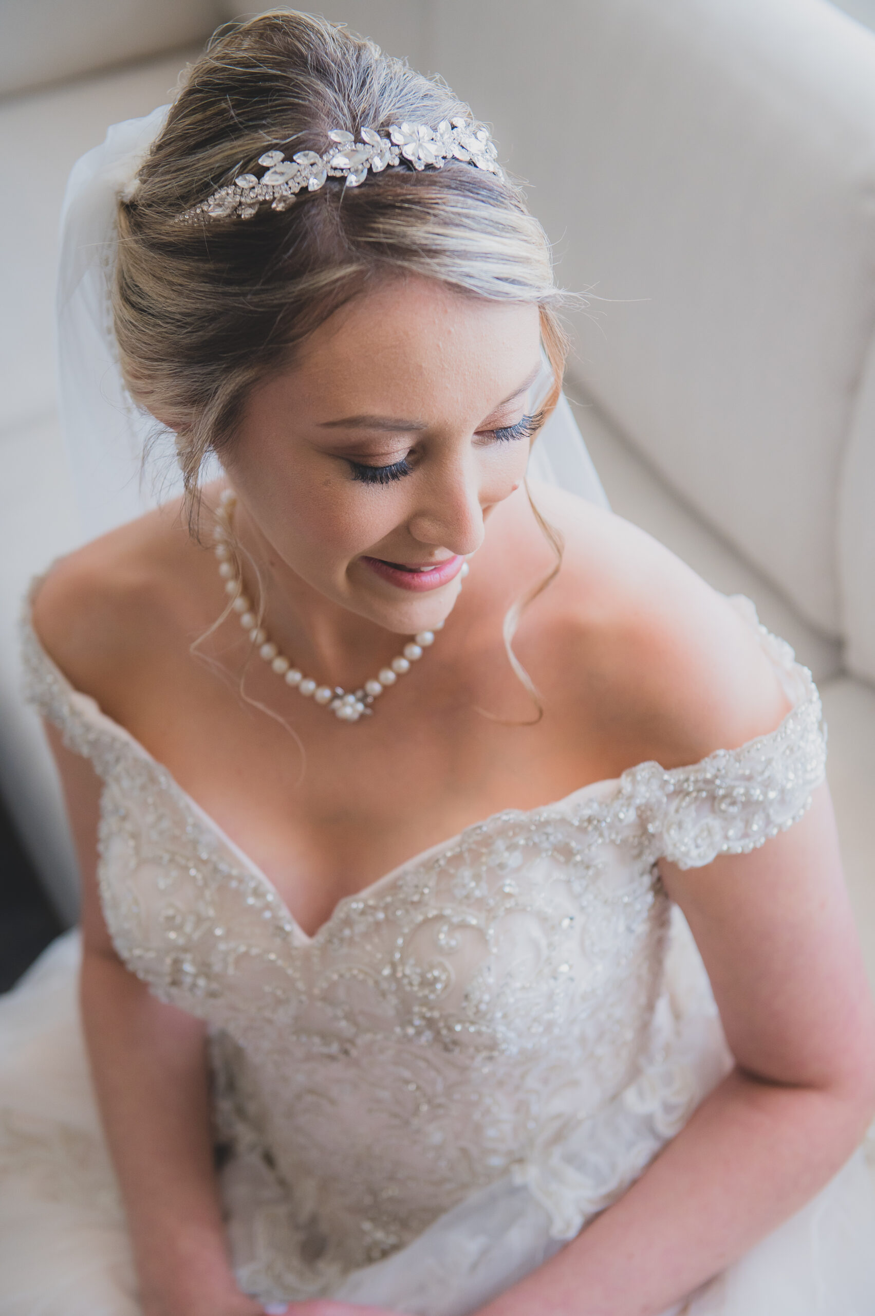bride in off shoulder embroidered wedding gown with pearl necklace and floral headpiece
