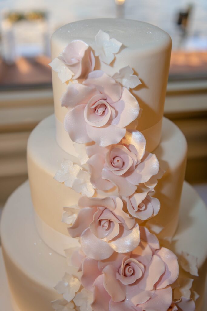 tiered white wedding cake decorated with large roses