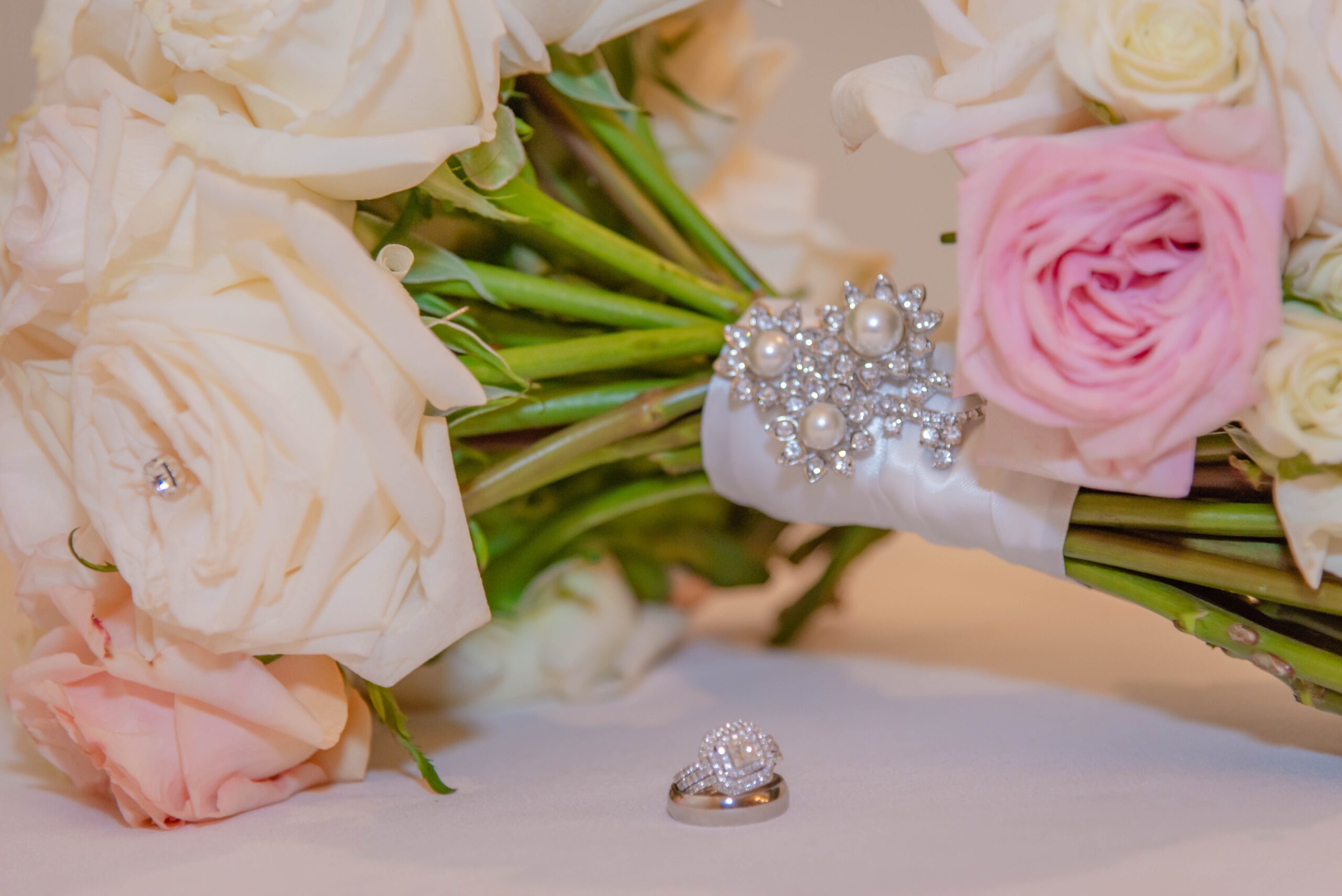 wedding rings by white and pink bridal bouquet
