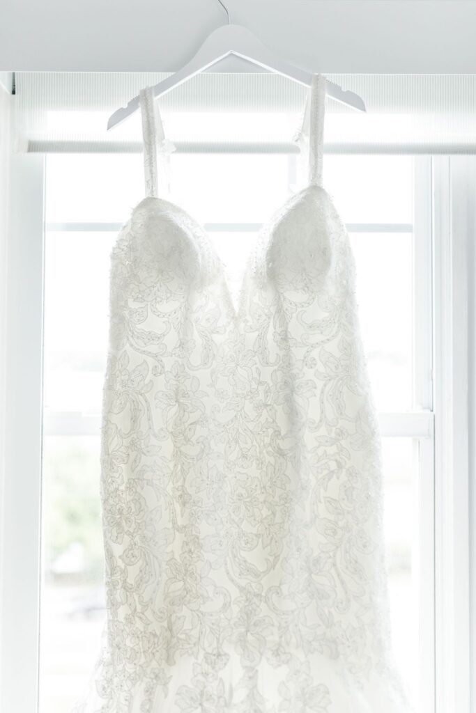 embroidered tulle wedding gown hanging by window